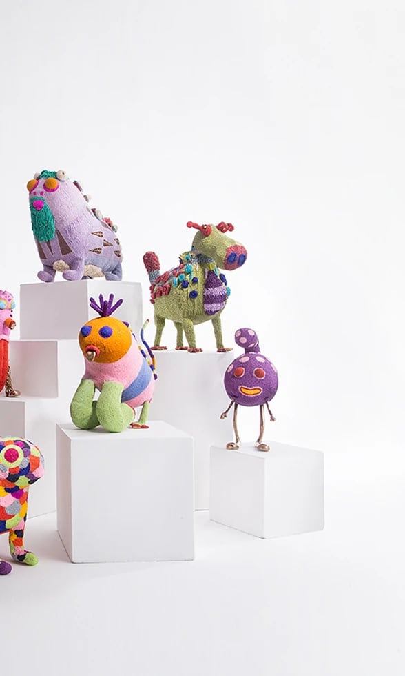 Colorful beaded sculptural creatures by the Haas Brothers, arranged on white plinths — right view